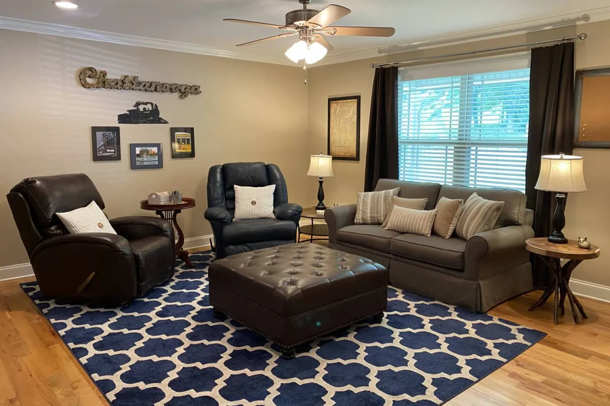 A view of another living area featuring recliner chairs, a sofa, a coffee table, and decorative wall art. The setup is intimate and ideal for quiet moments or smaller group gatherings, offering a distinct but equally inviting lounge experience.